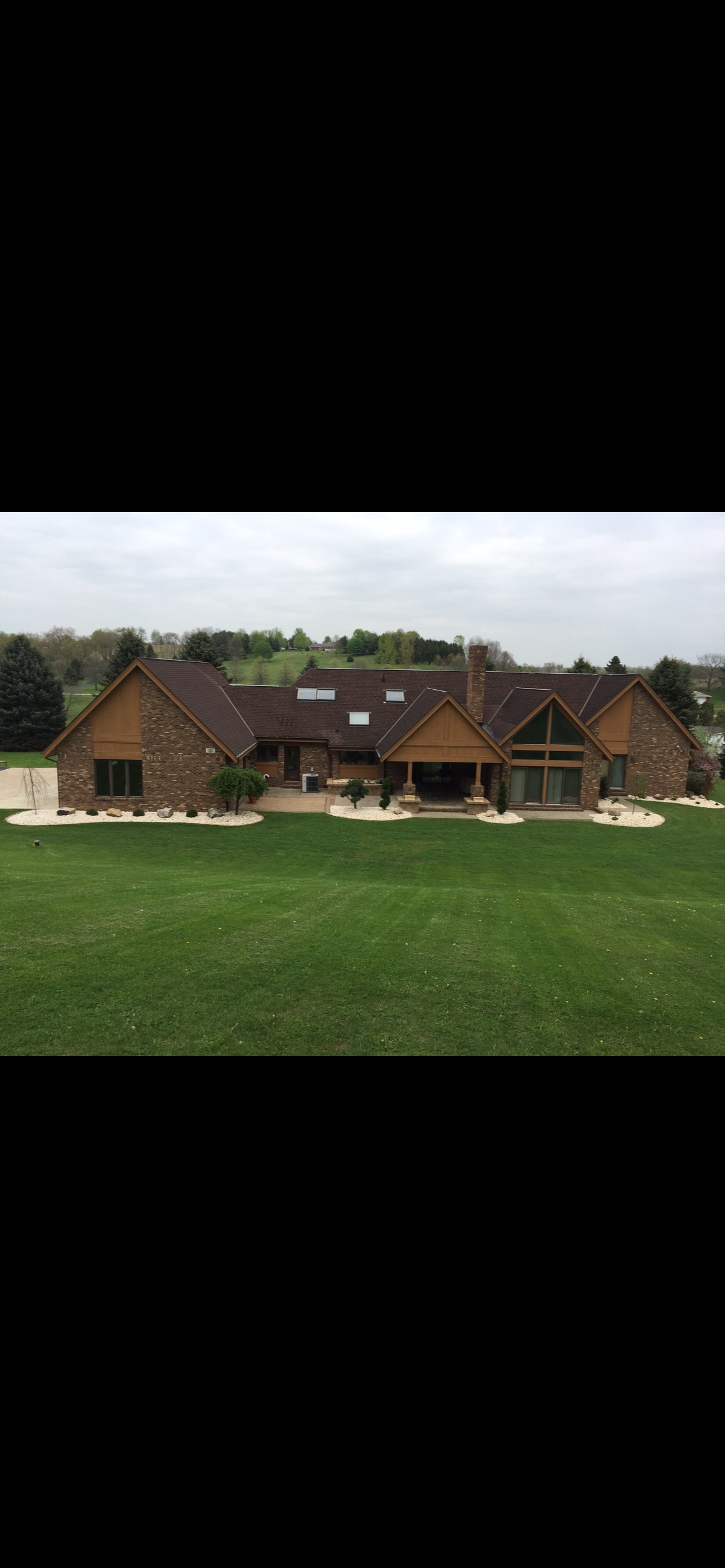 Large brick home with multiple rooflines and a wide, manicured front lawn.